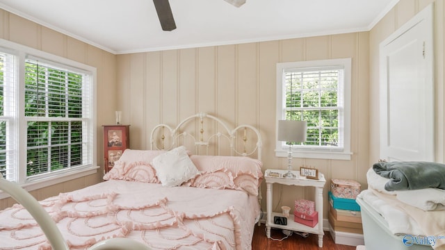 bedroom featuring ceiling fan, crown molding, wood finished floors, and multiple windows