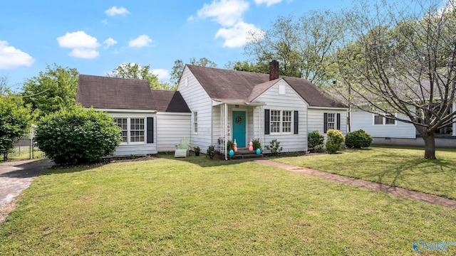 view of front facade featuring a chimney, a shingled roof, entry steps, and a front yard