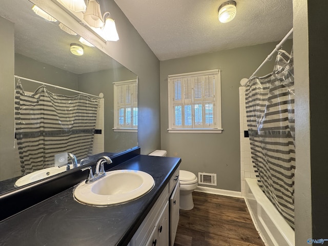 full bathroom featuring shower / tub combo with curtain, vanity, wood-type flooring, a textured ceiling, and toilet