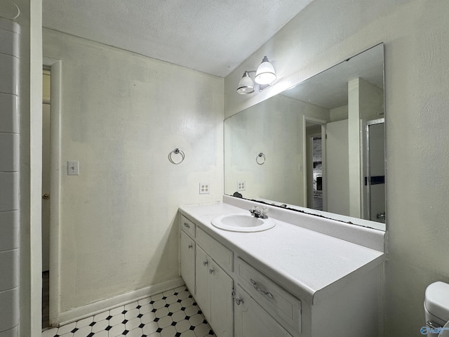 bathroom featuring vanity, toilet, and a textured ceiling