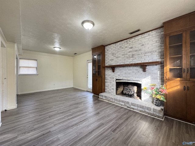 unfurnished living room with wood-type flooring, crown molding, a textured ceiling, and a fireplace