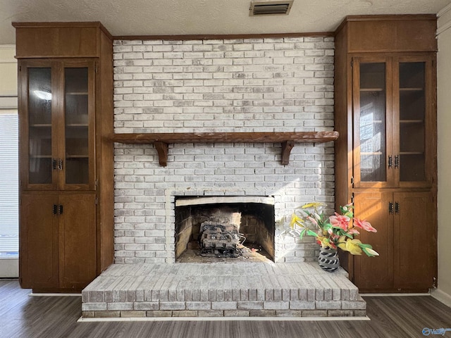 interior details featuring a brick fireplace, wood-type flooring, and a textured ceiling