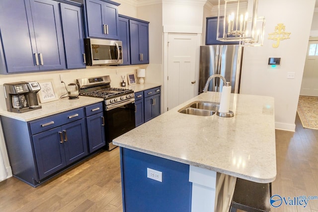 kitchen featuring appliances with stainless steel finishes, blue cabinets, sink, light hardwood / wood-style flooring, and an island with sink