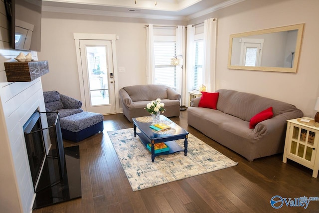 living room featuring dark hardwood / wood-style floors, a tray ceiling, and crown molding