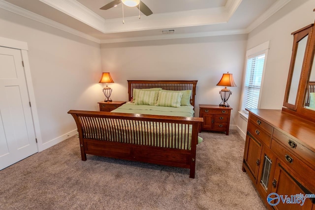 carpeted bedroom with a raised ceiling, ceiling fan, and crown molding