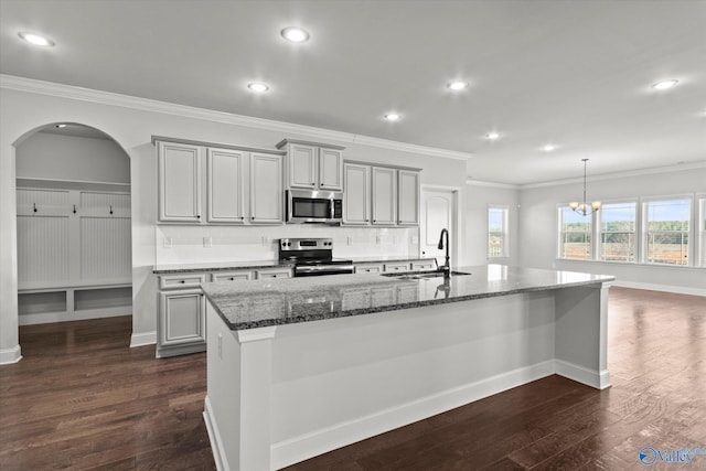 kitchen with dark stone countertops, a center island with sink, appliances with stainless steel finishes, gray cabinetry, and sink