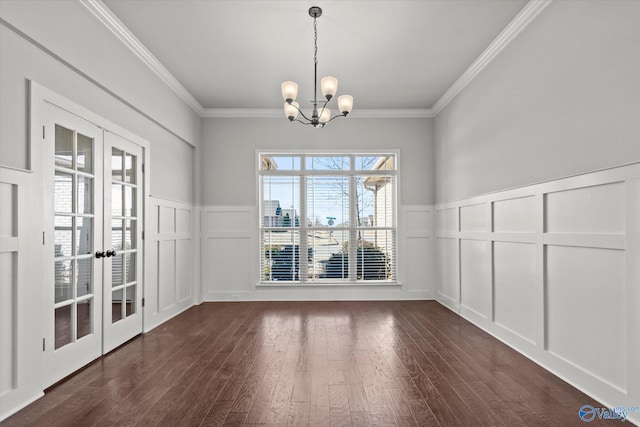 unfurnished dining area with a notable chandelier, dark wood-type flooring, french doors, and ornamental molding