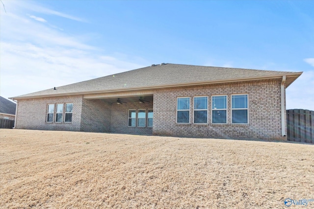 back of property with a yard and ceiling fan