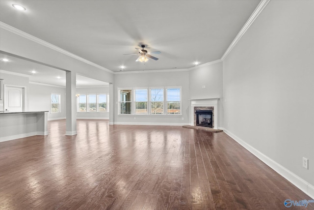 unfurnished living room featuring a fireplace, dark wood-type flooring, ceiling fan, and crown molding