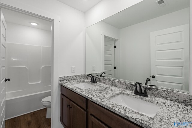 full bathroom with vanity, hardwood / wood-style floors, washtub / shower combination, and toilet