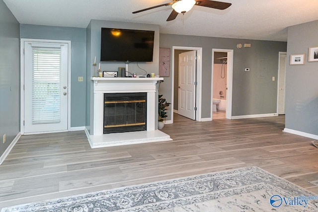 4967 Seven Pine Cir Unit 4967, Huntsville, AL 35816 - unfurnished living room featuring ceiling fan, a glass covered fireplace, wood finished floors, and baseboards