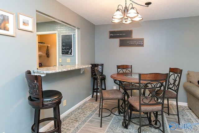 4967 Seven Pine Cir Unit 4967, Huntsville, AL 35816 - dining area featuring light wood-style floors, baseboards, a chandelier, a bar, and a textured ceiling