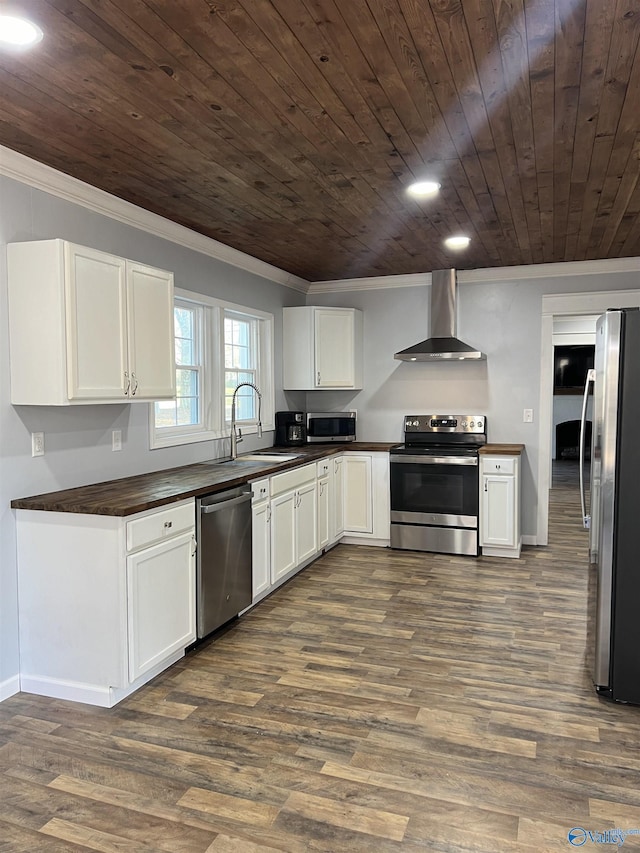 kitchen featuring appliances with stainless steel finishes, sink, white cabinets, crown molding, and wall chimney exhaust hood