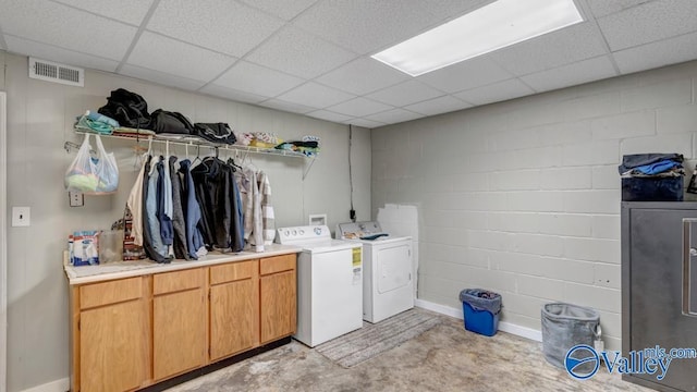 clothes washing area featuring separate washer and dryer and cabinets