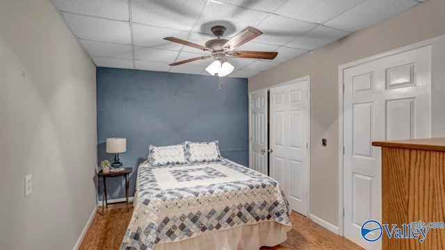 bedroom featuring ceiling fan, wood-type flooring, and a drop ceiling