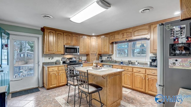 kitchen featuring sink, crown molding, a center island, stainless steel appliances, and backsplash