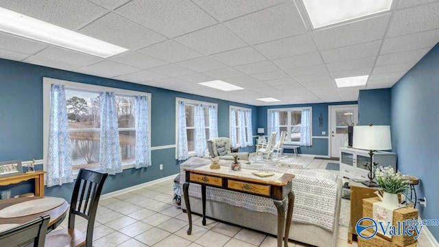 tiled living room featuring plenty of natural light and a paneled ceiling