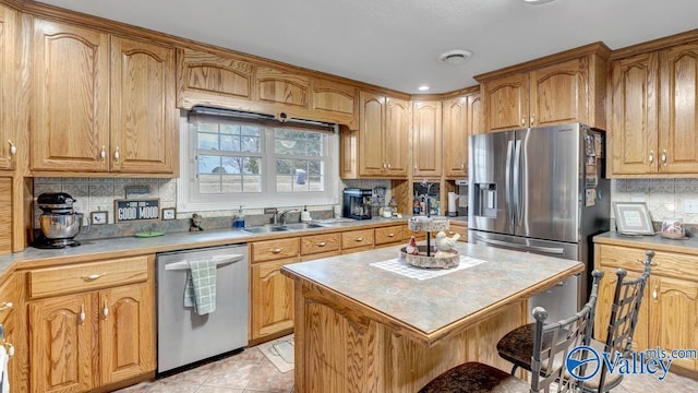 kitchen with sink, tasteful backsplash, light tile patterned floors, appliances with stainless steel finishes, and a kitchen island