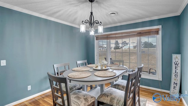 dining space featuring an inviting chandelier, ornamental molding, and hardwood / wood-style floors