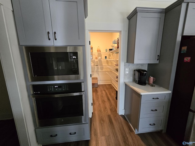 kitchen featuring oven, refrigerator, gray cabinets, built in microwave, and dark hardwood / wood-style flooring