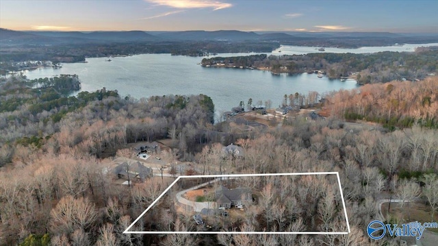 aerial view at dusk featuring a water and mountain view