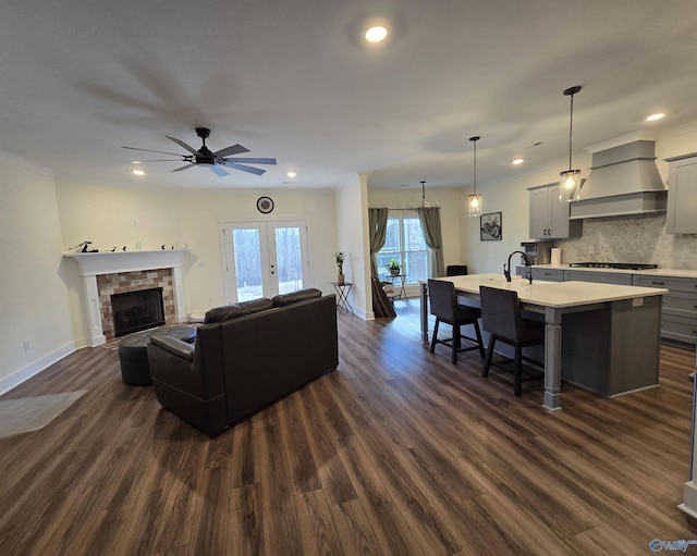 living room featuring ceiling fan, french doors, sink, dark wood-type flooring, and a fireplace