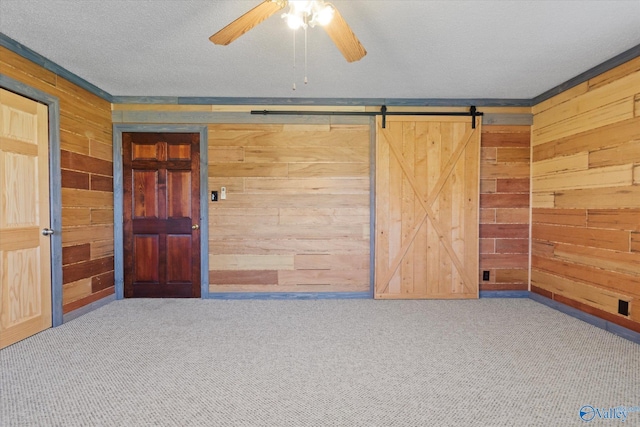 carpeted empty room with a textured ceiling, ceiling fan, and wooden walls