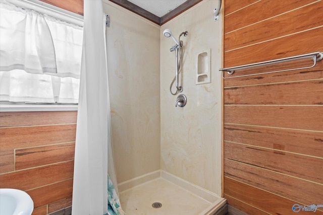 bathroom with a stall shower and wood walls