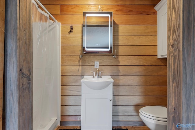 bathroom with vanity, wood walls, toilet, and curtained shower