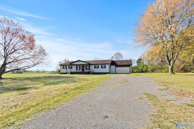 ranch-style home with gravel driveway, a front yard, and a garage