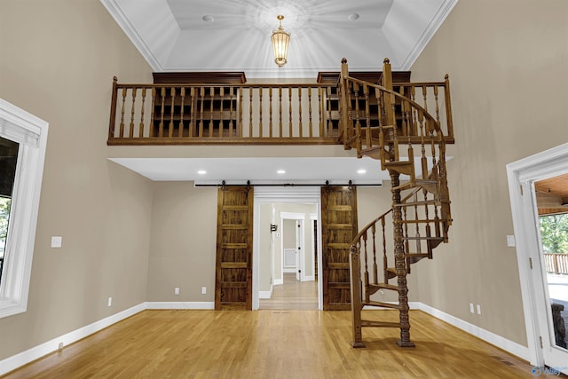 interior space featuring a barn door, hardwood / wood-style floors, crown molding, and vaulted ceiling