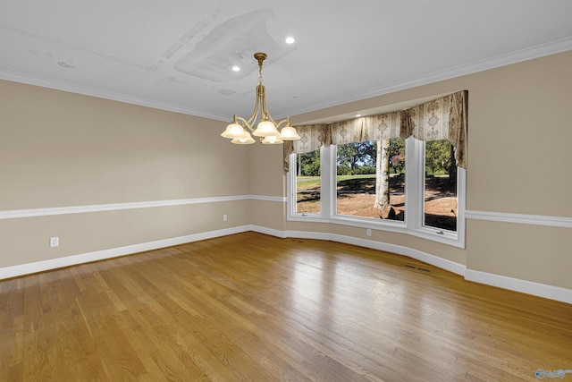 empty room with ornamental molding, a chandelier, and hardwood / wood-style floors