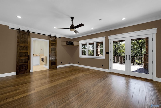 unfurnished living room featuring crown molding, hardwood / wood-style flooring, ceiling fan, and a barn door