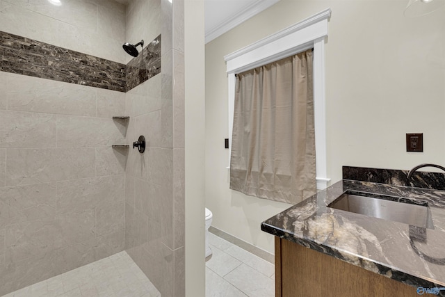 bathroom featuring toilet, tile patterned flooring, crown molding, vanity, and a tile shower