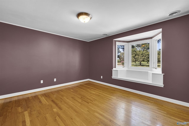 empty room featuring hardwood / wood-style floors and crown molding