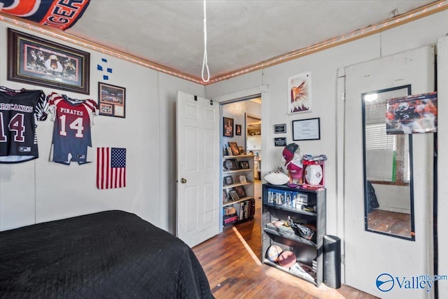 bedroom featuring wood-type flooring and crown molding