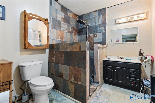 bathroom with toilet, vanity, and tiled shower