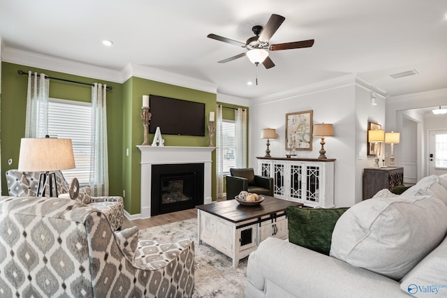 living room with crown molding, ceiling fan, and light wood-type flooring