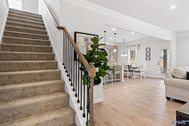 stairway with hardwood / wood-style flooring and ornamental molding