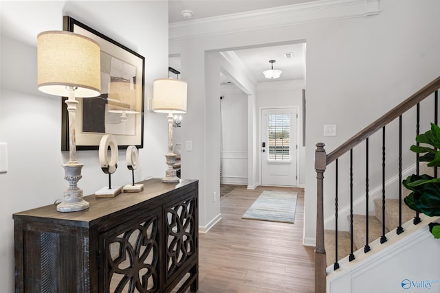 foyer with wood-type flooring and ornamental molding