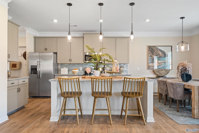 kitchen with a kitchen island, light stone countertops, appliances with stainless steel finishes, and decorative light fixtures