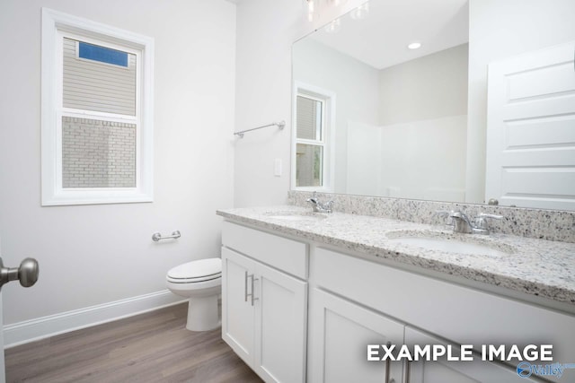 bathroom with toilet, baseboards, a sink, and wood finished floors