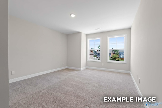 spare room with carpet, visible vents, and baseboards