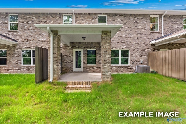 rear view of house featuring a patio, brick siding, a yard, and central AC