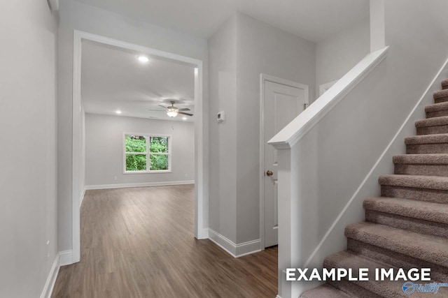 stairway featuring baseboards, wood finished floors, and ceiling fan
