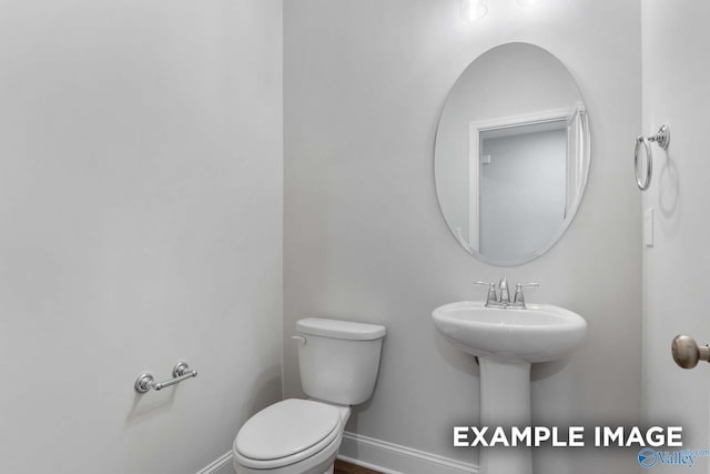 bathroom featuring toilet, a sink, and baseboards