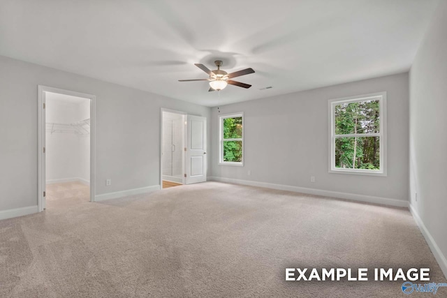 unfurnished bedroom with baseboards, a spacious closet, and carpet floors