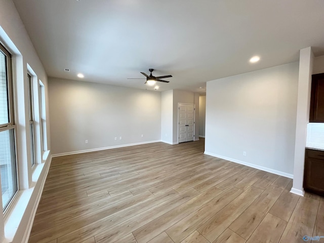 unfurnished living room with recessed lighting, light wood-style flooring, and baseboards