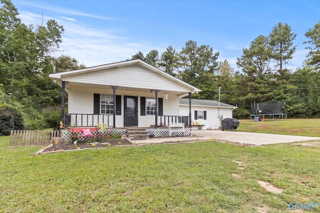 view of front of home with covered porch, a trampoline, and a front yard