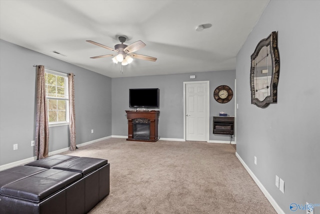 carpeted living room featuring a fireplace and ceiling fan